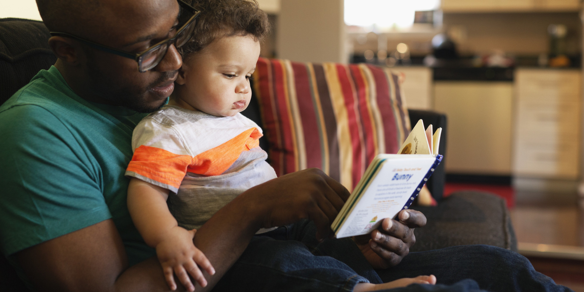 Father reading to baby on sofa